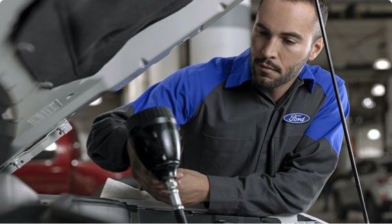 Close up of a technician performing a synthetic oil change on a modern SUV.