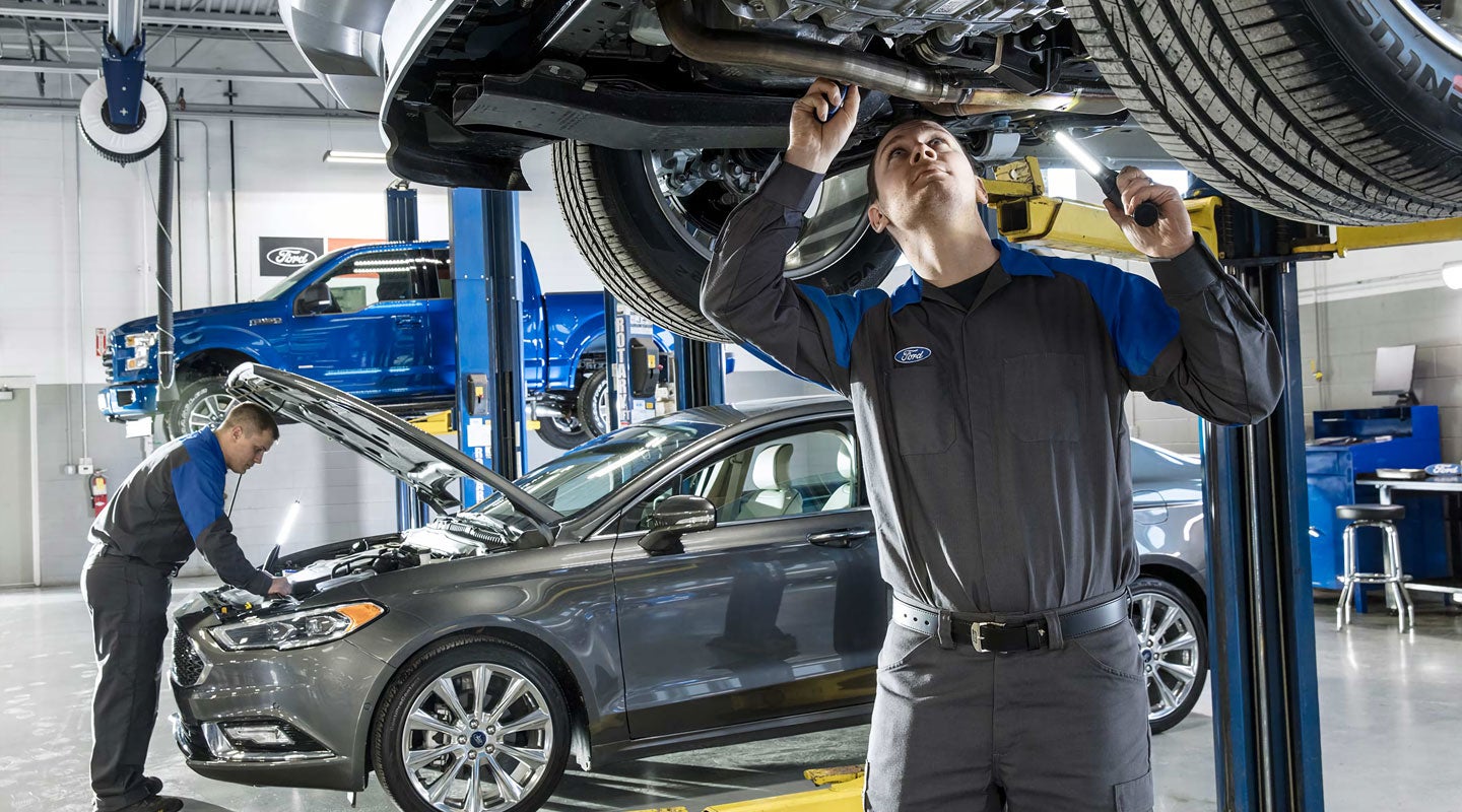 A professional automotive service bay with a technician working on a modern Ford truck in a clean, state-of-the-art facility.